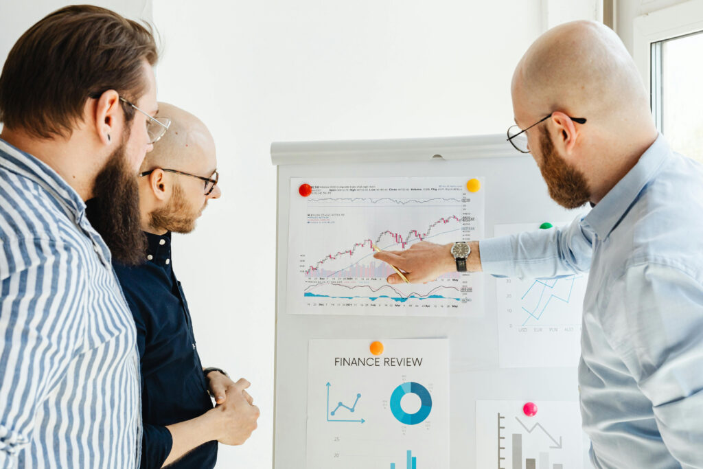 image of three white men looking at a graph on a white board.