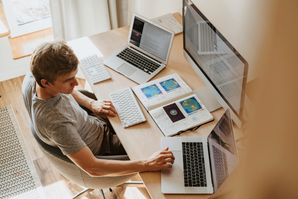 Image of a man sitting on his desk working with screens in front of him