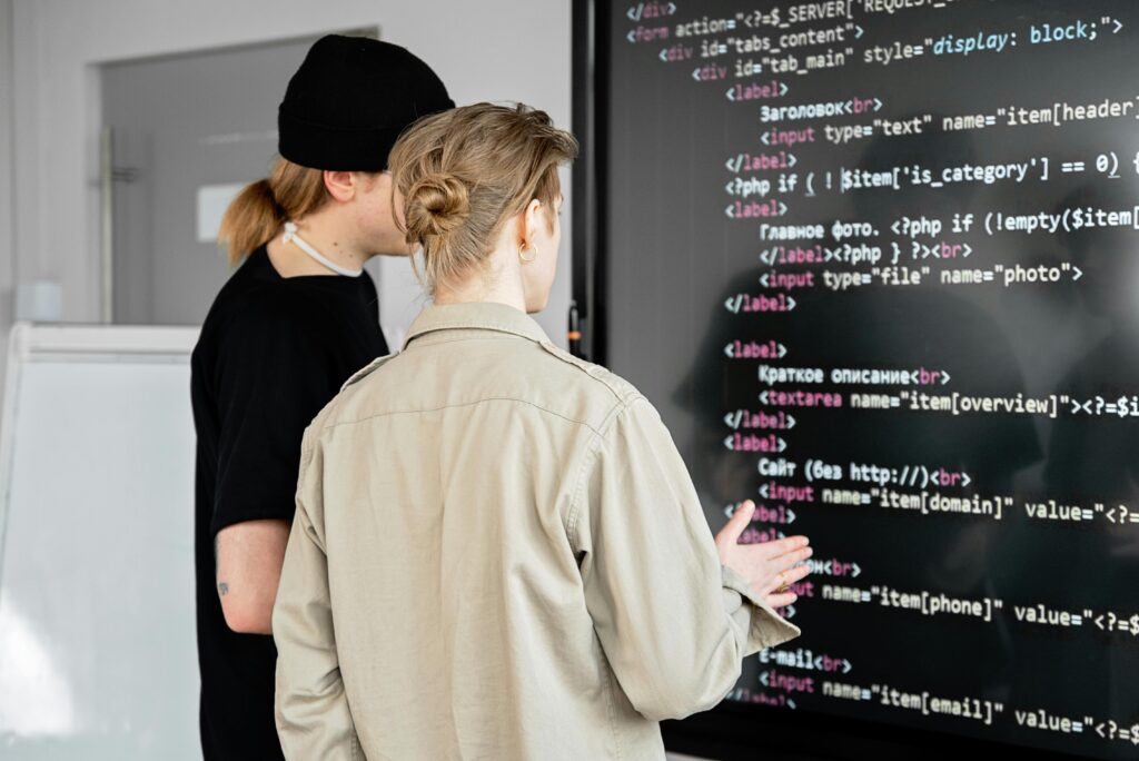 two men staring at a big screen displaying lines of code